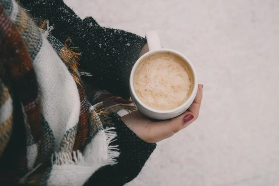 Hand holding a warm drink on a snowy winter day, when hands get dry and cracked